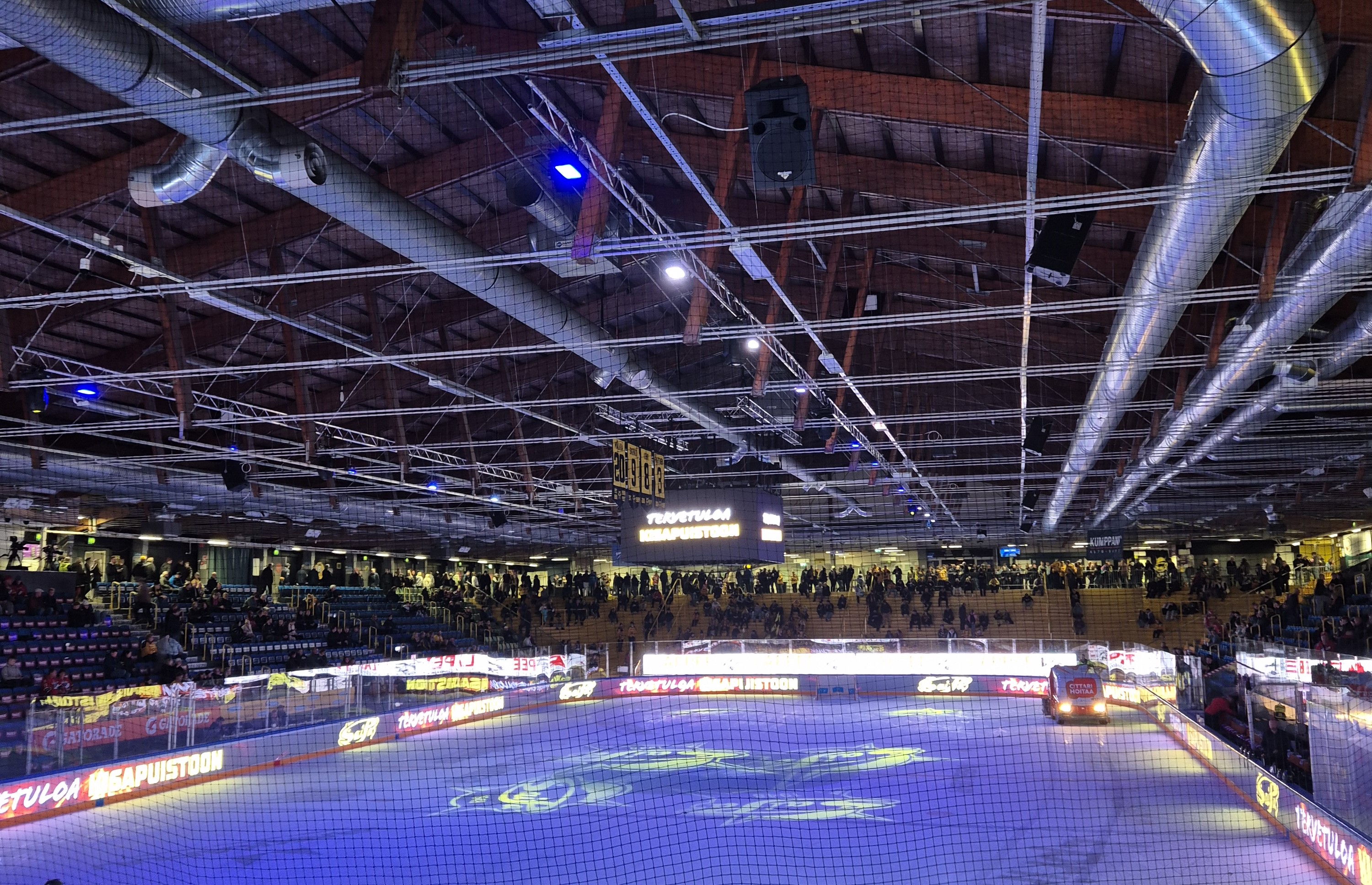 Kisapuiston jää hohtaa sinistä valoa. Kuvan yläosassa näkyy kattorakenteet, joissa menee putkia.